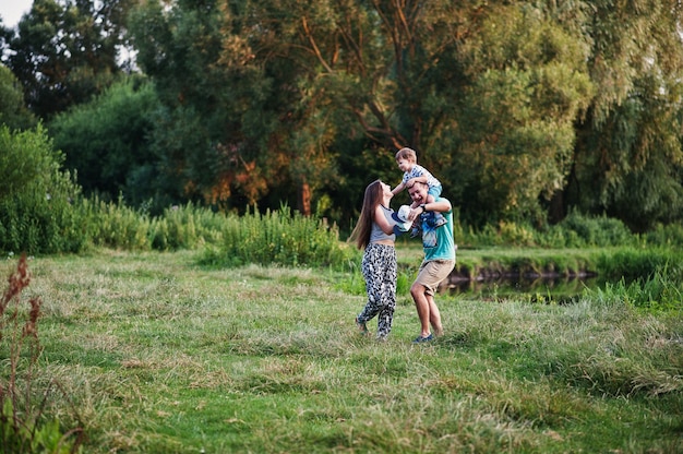 Familia joven feliz: madre, padre, hijo de niños en la naturaleza divirtiéndose.