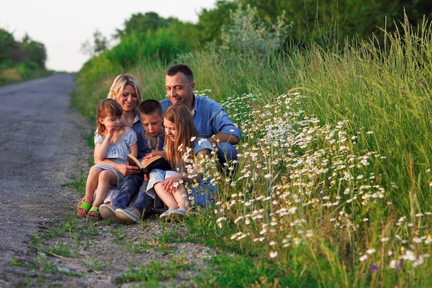 Familia joven y feliz con niños leyendo la Biblia en la naturaleza