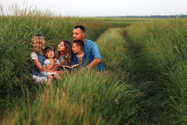 Foto familia joven y feliz con niños leyendo la biblia en la naturaleza