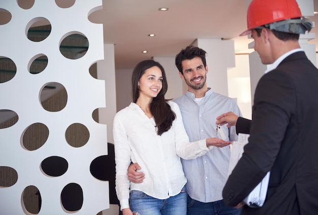 familia joven feliz, pareja comprando casa nueva con agente inmobiliario, interior de grupo de personas