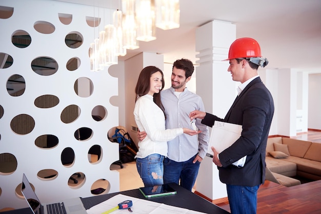 familia joven feliz, pareja comprando casa nueva con agente inmobiliario, interior de grupo de personas