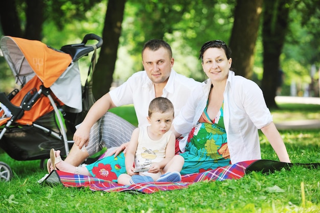 Familia joven feliz en el parque relajándose y divirtiéndose con una mujer embarazada