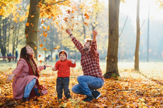 Familia joven feliz pasar tiempo al aire libre en el parque de otoño