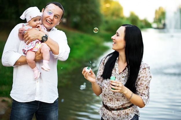 Familia joven feliz pasar tiempo juntos afuera en la naturaleza verde