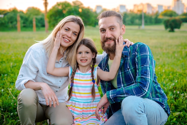 Familia joven feliz pasar tiempo juntos afuera en la naturaleza verde.