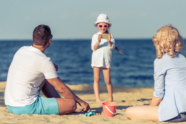 Familia joven feliz en la playa en ver.