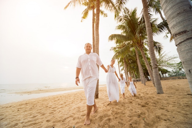 Familia joven feliz en la puesta de sol en la playa.