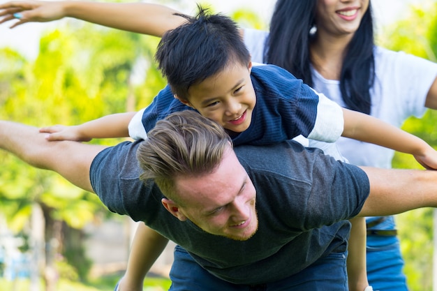 Familia joven feliz que pasa el tiempo junto afuera en naturaleza verde.