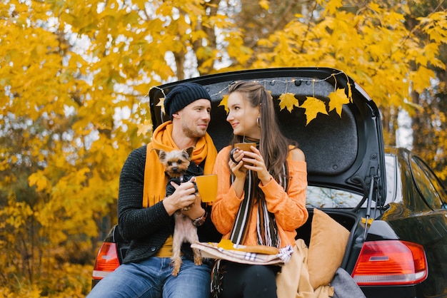 Una familia joven feliz se relaja después de un día al aire libre en el bosque de otoño