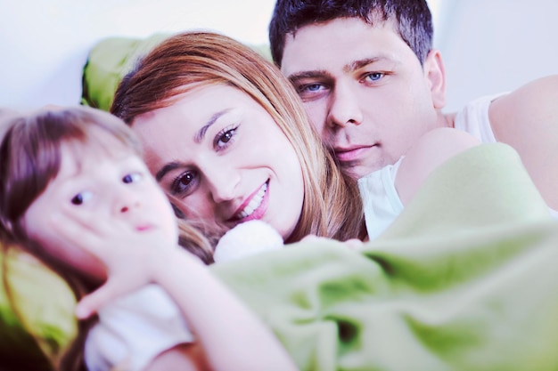 familia joven feliz relajándose en la cama