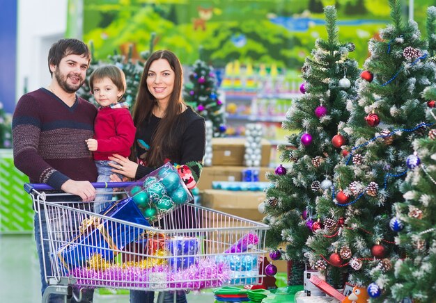 Familia joven feliz en el supermercado elige regalos para navidades