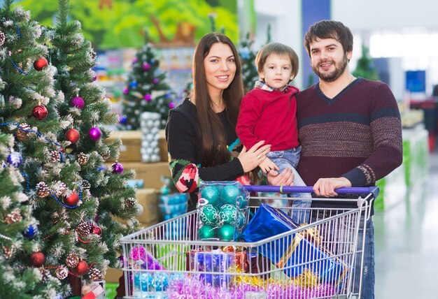 Familia joven feliz en el supermercado elige regalos para el nuevo año.