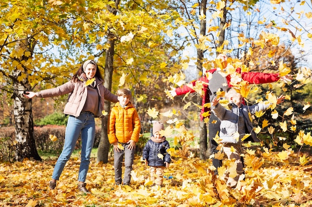 Familia joven feliz con tres hijos en el parque de otoño. Amor y ternura. Camina en la temporada dorada.