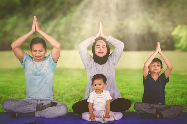 Familia joven haciendo ejercicios de yoga en el parque