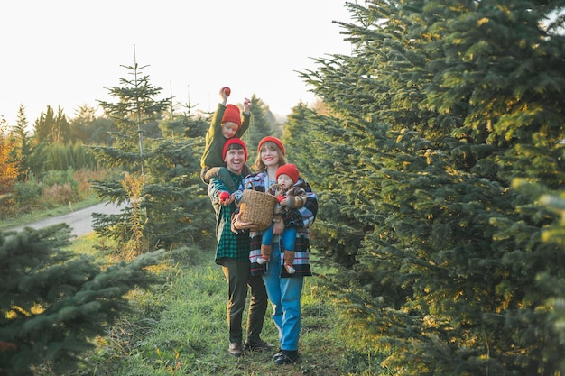 Una familia joven y hermosa elige un árbol de Navidad en el mercado Vacaciones de invierno festivas para padres y niños pequeños respetuosos con el medio ambiente