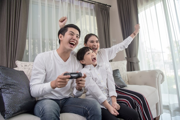 Familia joven jugando videojuegos juntos en casa y divirtiéndose juntos.