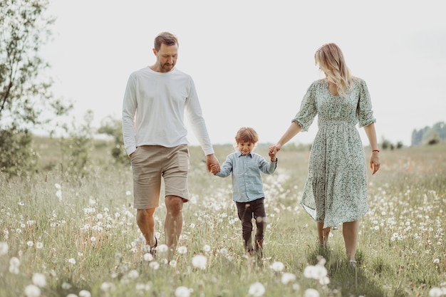 Familia joven juguetona con un niño que se divierte en la pradera de verano, concepto de familia feliz