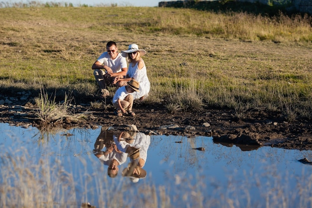 Una familia joven junto al estanque mira su reflejo.