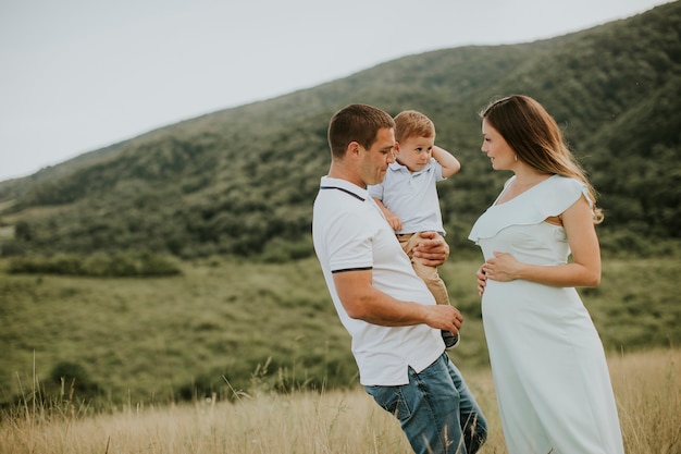 Familia joven con lindo niño divirtiéndose al aire libre en el campo de verano