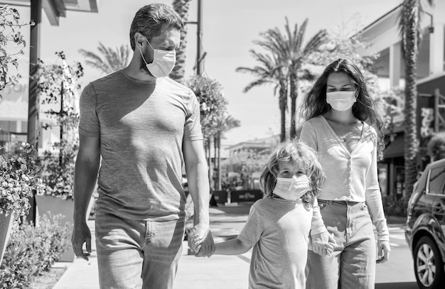 La familia joven de madre, padre e hijo usa una máscara protectora para caminar al aire libre, cuidado de la salud familiar