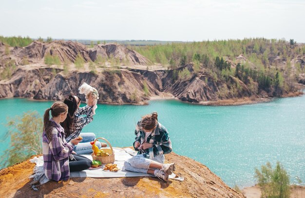 Familia joven de mamá e hijos con perro blanco en picnic después de hacer senderismo en las montañas hermosa vista del lago azul