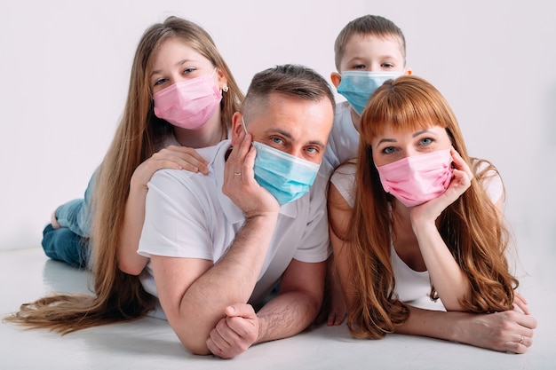 Familia joven en máscaras médicas durante la cuarentena domiciliaria.