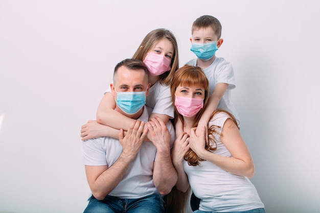 Foto familia joven en máscaras médicas durante la cuarentena domiciliaria.