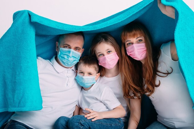Foto familia joven en máscaras médicas durante la cuarentena domiciliaria.