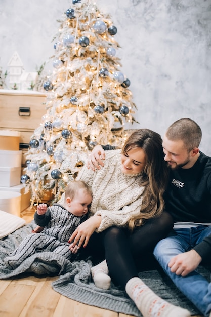 Familia joven con un niño en el interior, ambiente navideño,