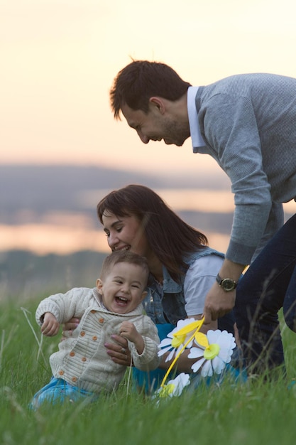 Foto una familia joven con un niño jugando y divirtiéndose en la naturaleza con un teleobjetivo al atardecer