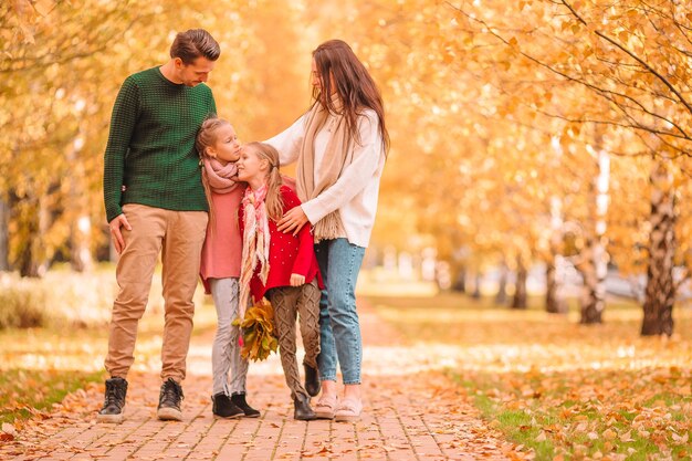 Familia joven con niños pequeños en el parque de otoño en un día soleado. Retrato de otoño familiar