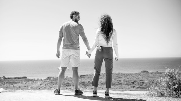 Familia joven pareja tomados de la mano mirando el agua de mar desde la libertad superior