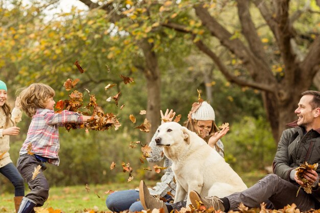 Familia joven con un perro en hojas