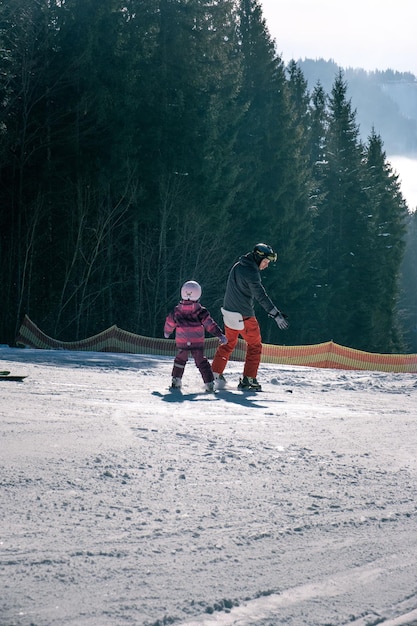 Familia joven en la pista de esquí enseñando a la hija esquiadora