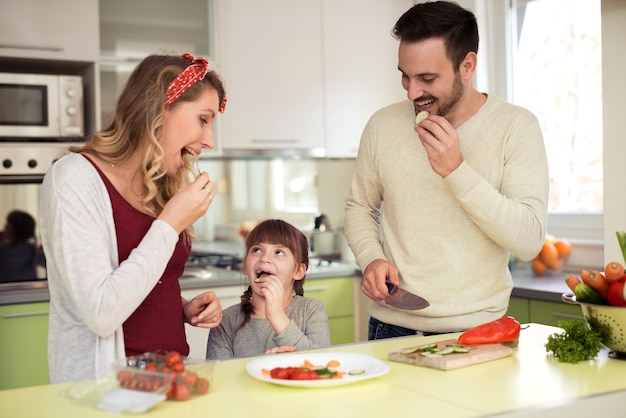 Familia joven preparando ensalada juntos