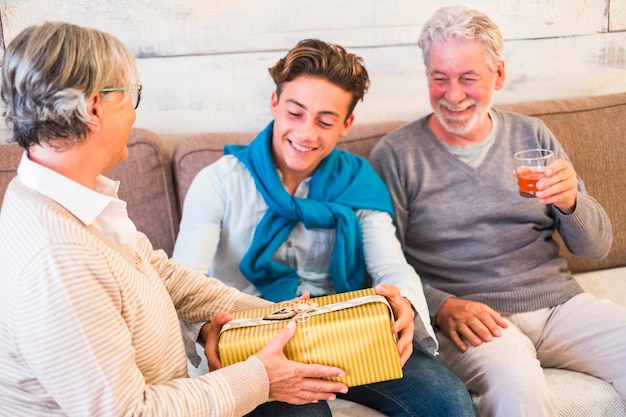 Familia joven y senior alegre dando regalos en navidad