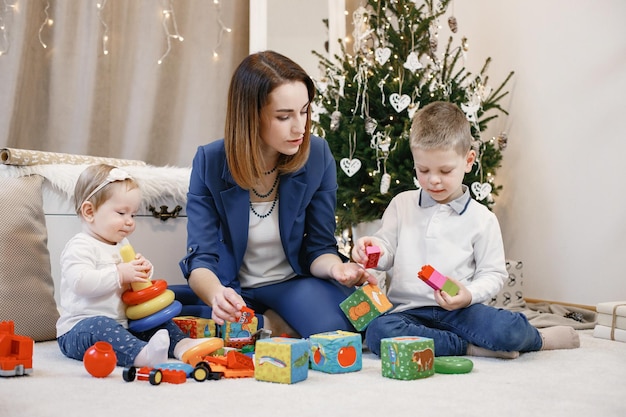 Familia joven sentada y jugando juntos cerca del árbol de navidad en casa