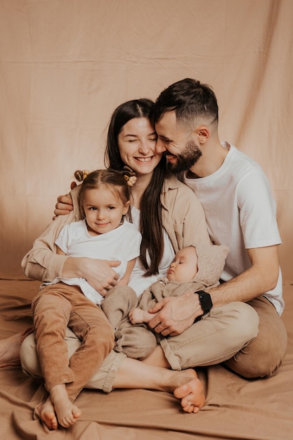 Una familia joven y sincera donde un elegante padre barbudo y una linda esposa sostienen a sus lindos hijos.