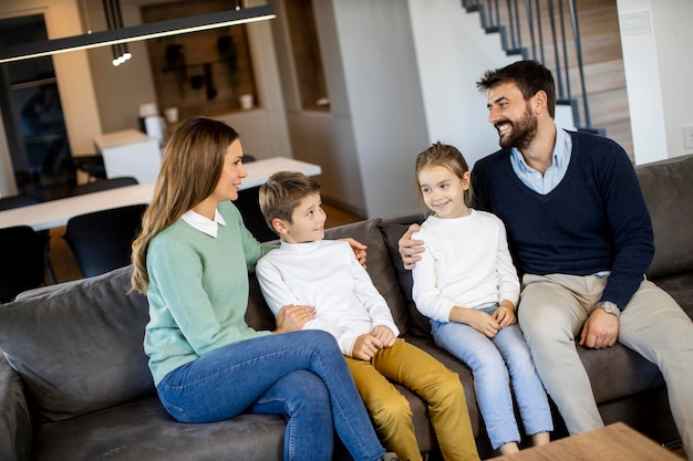 Familia joven sonriente viendo la televisión juntos en el sofá de la sala de estar