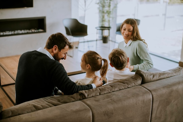 Familia joven sonriente viendo la televisión juntos en el sofá de la sala de estar