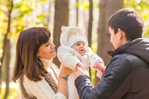 Familia joven con su bebé recién nacido pasar tiempo al aire libre en el parque de otoño.
