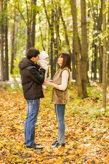 Familia joven con su bebé recién nacido pasar tiempo al aire libre en el parque de otoño.