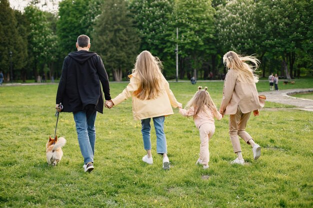 Familia joven y su perro corgi caminando juntos en un parque