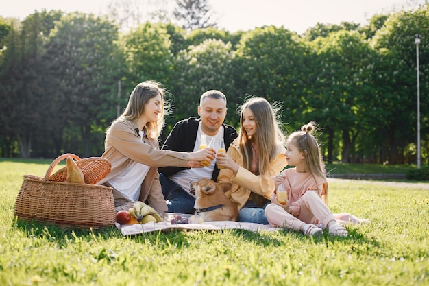 Familia joven y su perro corgi haciendo un picnic en un parque