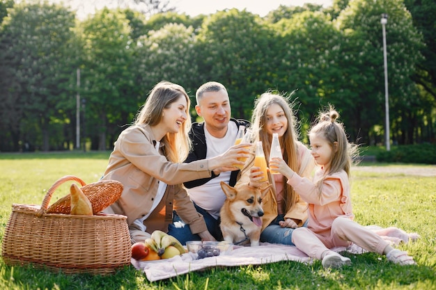 Familia joven y su perro corgi haciendo un picnic en un parque