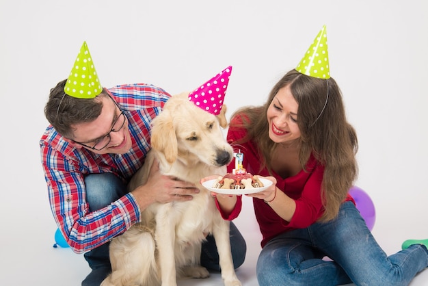 Familia joven con su perro golden retriever celebran el cumpleaños de un año.