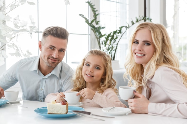 familia joven con tazas de café y pastel pasando tiempo en el café