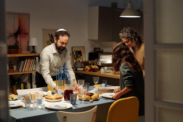 família judaica de três servindo mesa para o jantar de Hanukkah com comida caseira