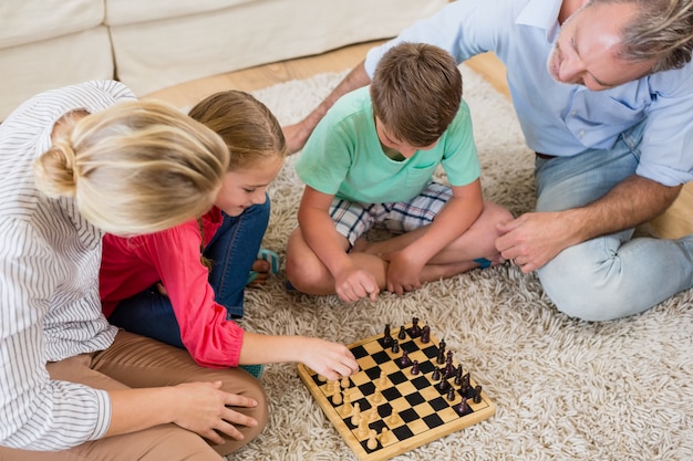 Familia jugando al ajedrez juntos en casa en la sala de estar