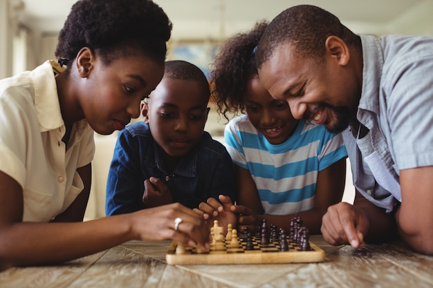 Familia jugando al ajedrez juntos en casa en la sala de estar